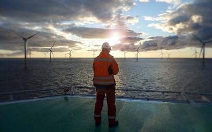 Man standing in front of an off-shore wind farm