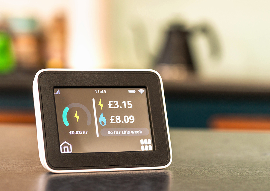 Close-up of the screen of a smart meter display in a kitchen, showing the cost of electricity and gas so far in the current week.