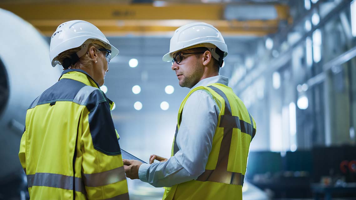 Two Industry Engineers Stand in Pipe Manufacturing Factory