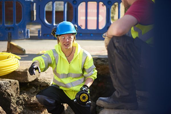 civil engineer a female gas engineer holds a new gas valve as she and a colleague prepare to replace the old pipework in a residential uk street .